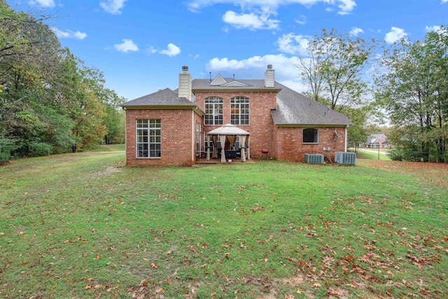 back of house with central AC unit and a yard