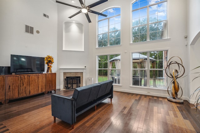 living room with dark wood-type flooring, a healthy amount of sunlight, and a towering ceiling