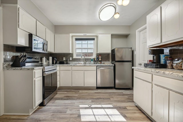 kitchen with light hardwood / wood-style flooring, white cabinetry, decorative backsplash, and stainless steel appliances