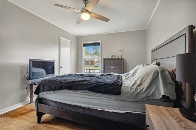 bedroom featuring ornamental molding, hardwood / wood-style floors, ceiling fan, and a textured ceiling