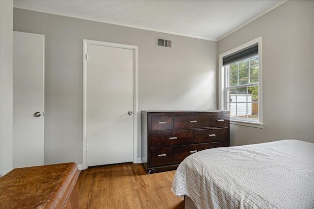 bedroom with light hardwood / wood-style floors and crown molding