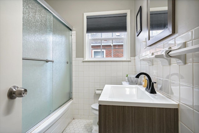 full bathroom featuring tile walls, vanity, bath / shower combo with glass door, tile patterned flooring, and toilet