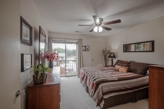 carpeted bedroom with ceiling fan, access to exterior, and a textured ceiling