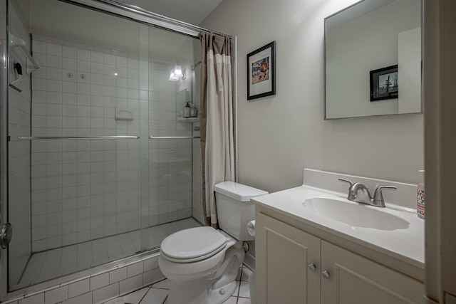 bathroom featuring toilet, vanity, tile patterned floors, and tiled shower