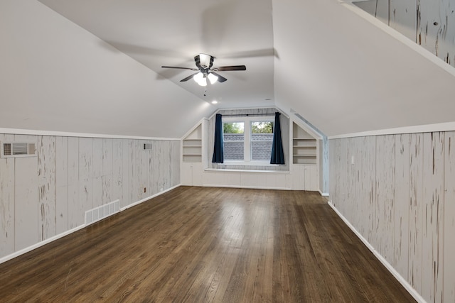 additional living space featuring lofted ceiling, dark hardwood / wood-style floors, built in features, and wooden walls