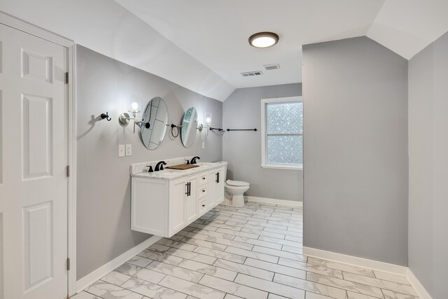 bathroom featuring vanity, lofted ceiling, and toilet