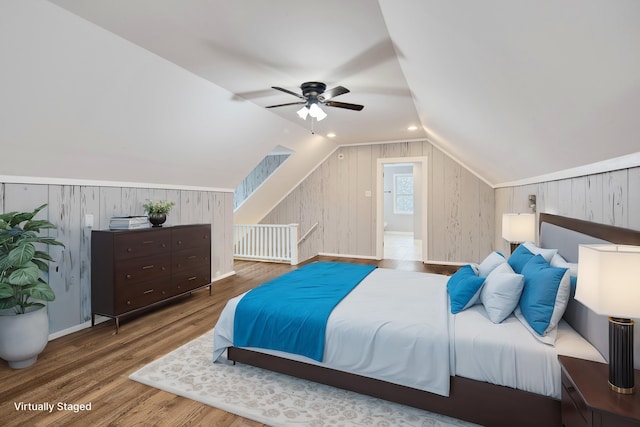 bedroom featuring lofted ceiling, hardwood / wood-style floors, ceiling fan, and wood walls