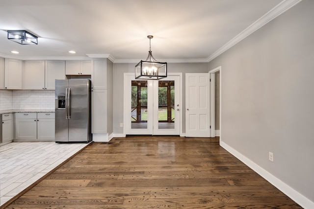 kitchen featuring stainless steel fridge with ice dispenser, decorative backsplash, hanging light fixtures, and white cabinets