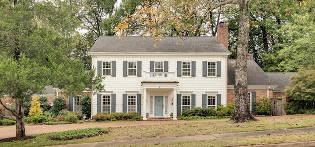 colonial inspired home featuring a front yard and a balcony