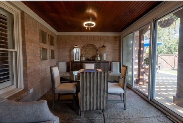 dining space featuring brick wall and wooden ceiling