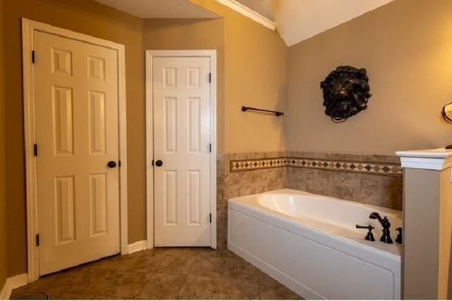 bathroom featuring tile patterned flooring, a washtub, and vaulted ceiling