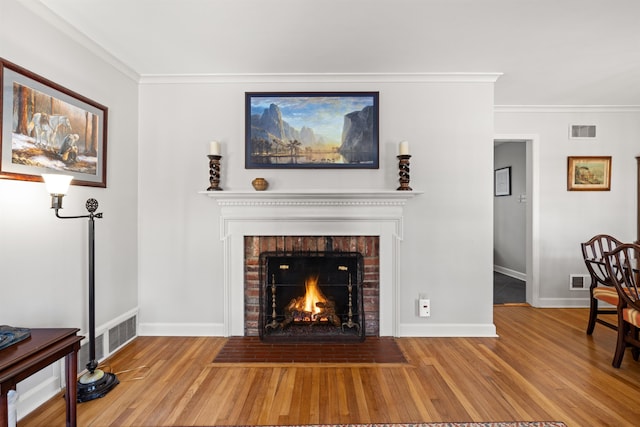 living room with wood-type flooring, ornamental molding, and a fireplace