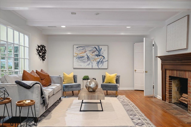 living room featuring a brick fireplace, light hardwood / wood-style flooring, and beam ceiling