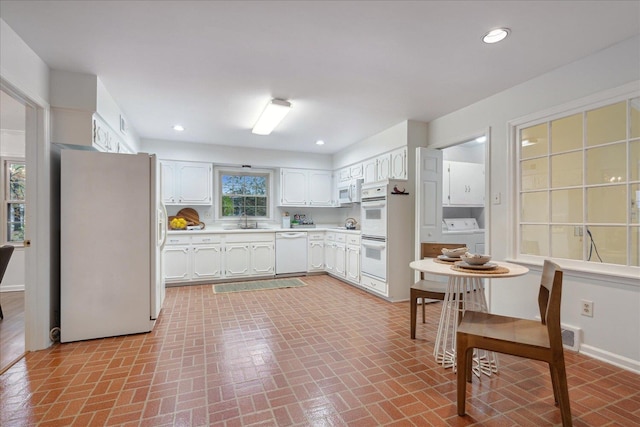 kitchen with white cabinetry, plenty of natural light, sink, and white appliances