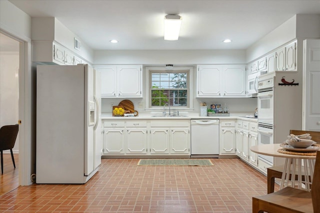 kitchen with white appliances, white cabinetry, and sink