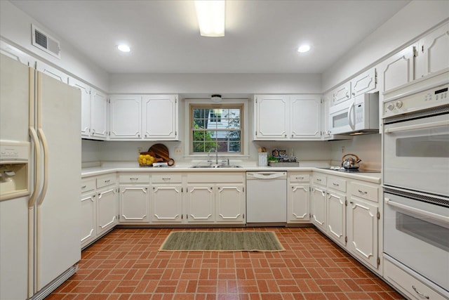 kitchen with white appliances, sink, and white cabinets