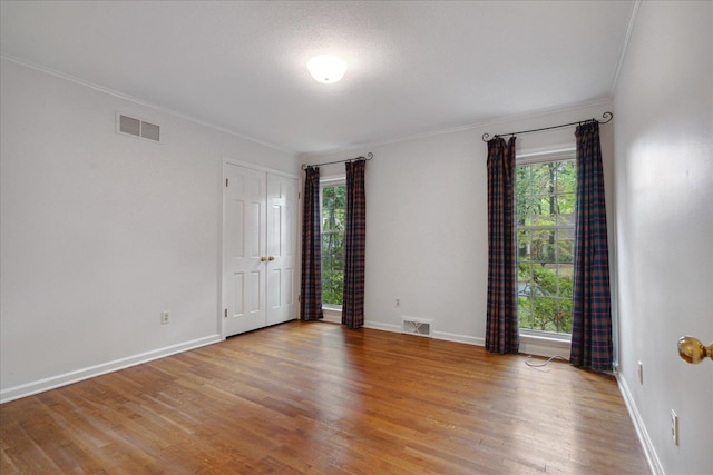 spare room featuring ornamental molding, a wealth of natural light, and light hardwood / wood-style floors