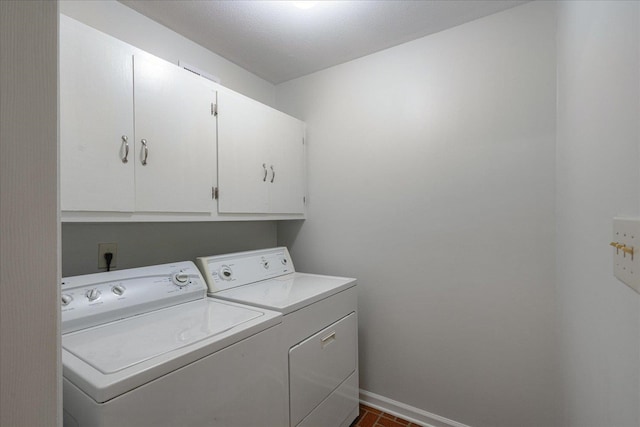 laundry area featuring a textured ceiling, separate washer and dryer, and cabinets