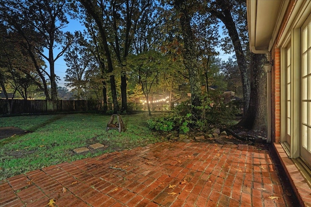 patio terrace at dusk featuring a lawn