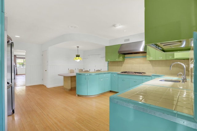 280 Waring Rd, Memphis, TN 38117 - kitchen with wall chimney exhaust hood, tasteful backsplash, light wood-style flooring, stainless steel appliances, and a wainscoted wall