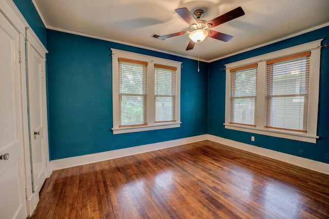 unfurnished bedroom featuring ceiling fan, dark hardwood / wood-style floors, crown molding, and multiple windows