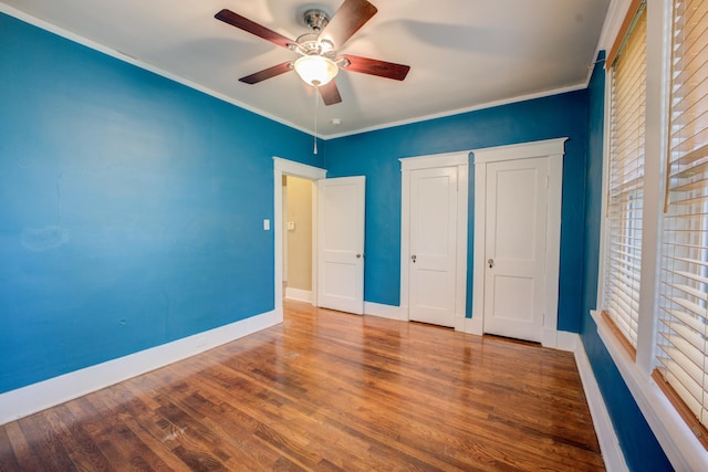 unfurnished bedroom featuring ceiling fan, hardwood / wood-style floors, and crown molding