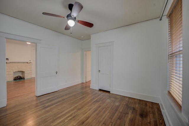 unfurnished bedroom with ceiling fan, dark hardwood / wood-style flooring, and a fireplace