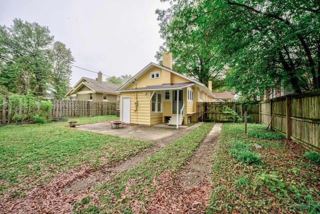 rear view of property featuring a patio and a fire pit