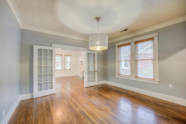 unfurnished dining area featuring wood-type flooring, ornamental molding, and french doors