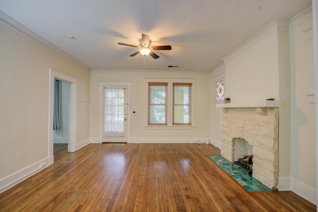 unfurnished living room featuring hardwood / wood-style flooring, ceiling fan, a stone fireplace, and crown molding