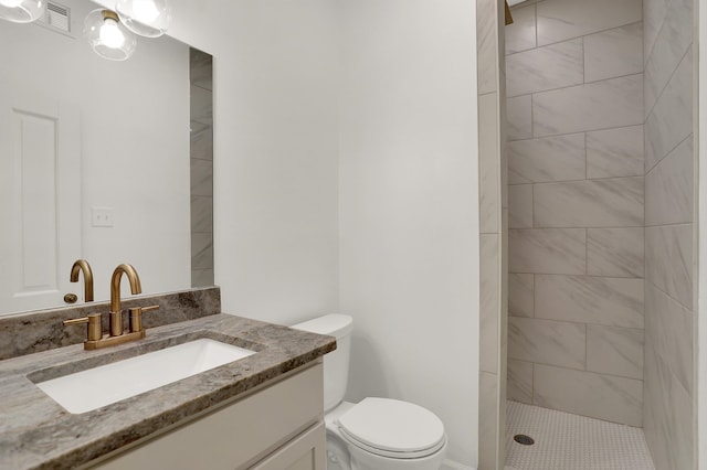 bathroom featuring toilet, vanity, and tiled shower