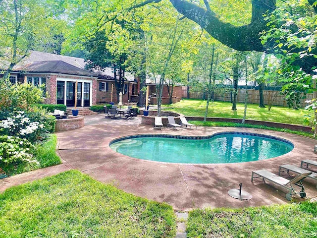 view of swimming pool featuring a patio, a lawn, and french doors