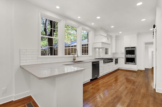 kitchen with hardwood / wood-style floors, custom range hood, white cabinetry, and sink