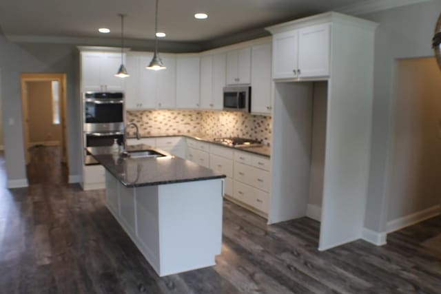 kitchen with dark wood-type flooring, appliances with stainless steel finishes, an island with sink, and white cabinets