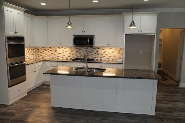 kitchen with dark hardwood / wood-style flooring, a kitchen island with sink, white cabinetry, appliances with stainless steel finishes, and dark stone countertops