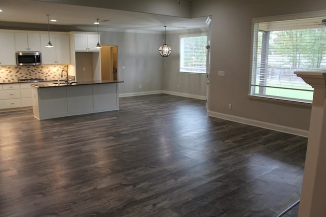 kitchen featuring stainless steel appliances, dark hardwood / wood-style flooring, white cabinets, hanging light fixtures, and sink