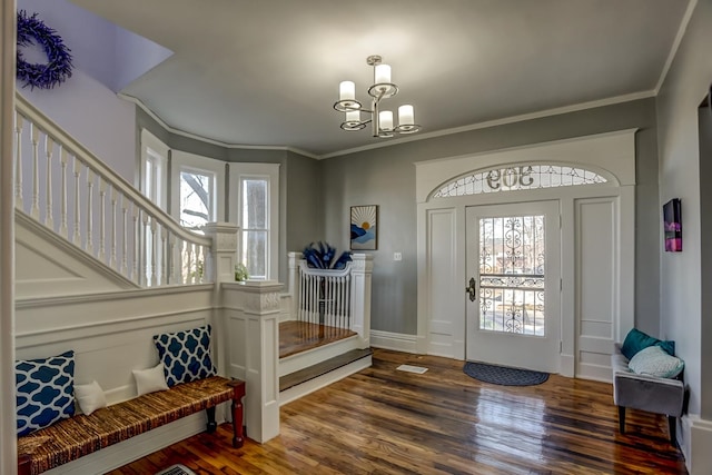 foyer featuring dark wood-type flooring, a healthy amount of sunlight, crown molding, and a notable chandelier