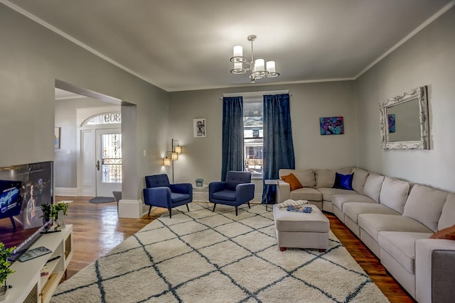 living room with hardwood / wood-style flooring, an inviting chandelier, and ornamental molding