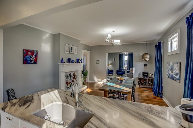 interior space with sink, a notable chandelier, ornamental molding, and wood-type flooring