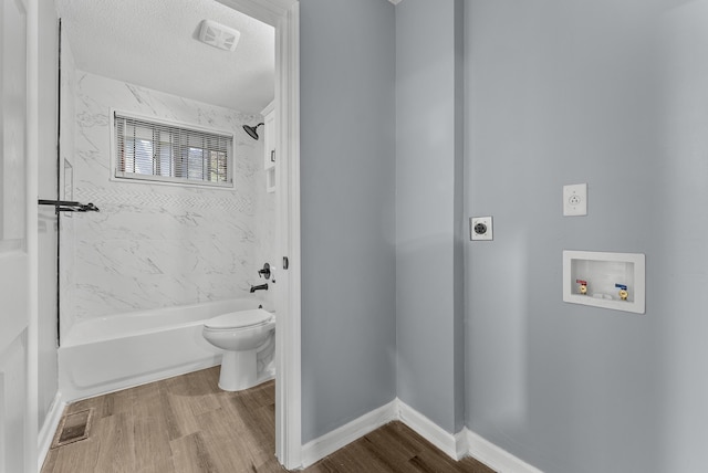 bathroom with hardwood / wood-style floors, tiled shower / bath, toilet, and a textured ceiling