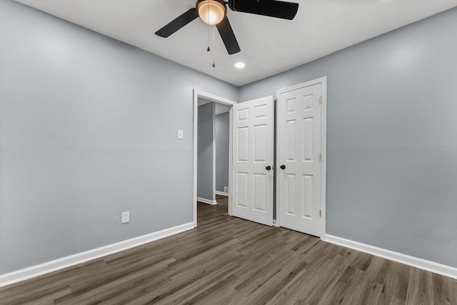 unfurnished bedroom featuring dark hardwood / wood-style flooring, ceiling fan, and a closet