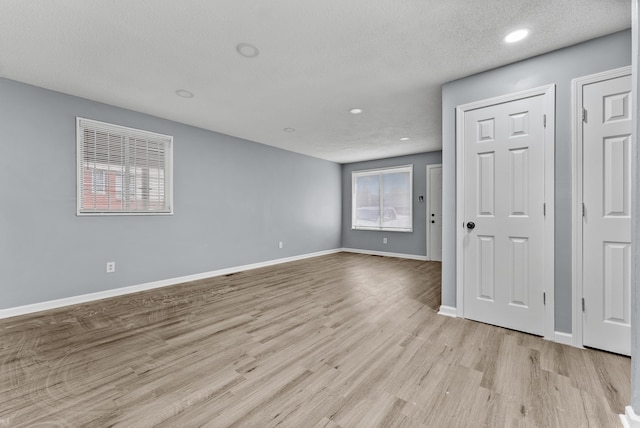 unfurnished room featuring a textured ceiling and light hardwood / wood-style flooring