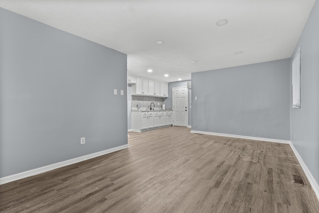 unfurnished living room with light hardwood / wood-style floors and sink