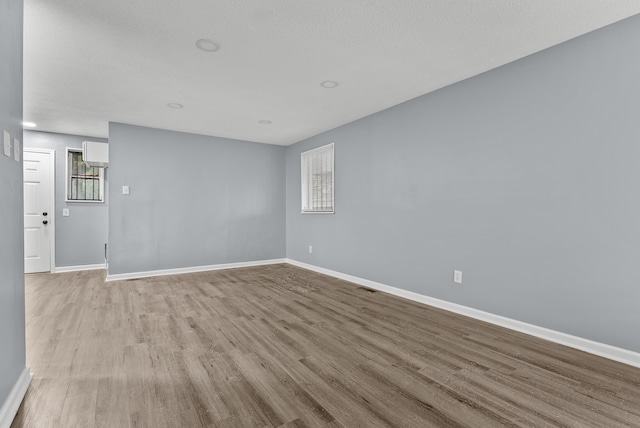 unfurnished room with a textured ceiling and light wood-type flooring