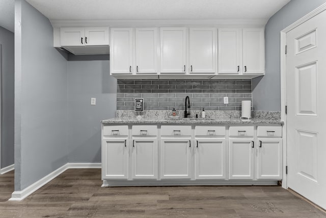 kitchen with white cabinetry, dark hardwood / wood-style floors, and light stone countertops