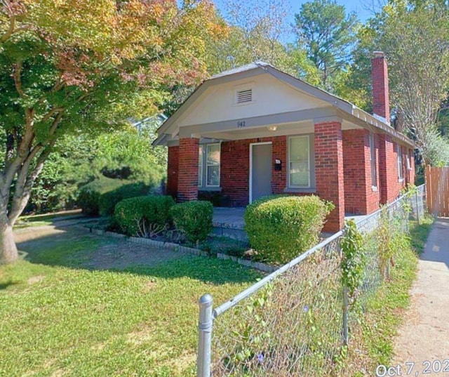 bungalow featuring a chimney, brick siding, and a porch