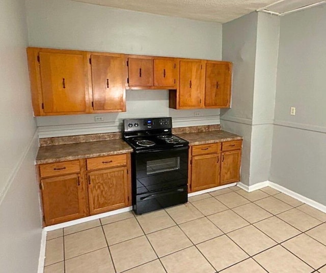 kitchen featuring black range with electric stovetop, brown cabinets, light tile patterned floors, baseboards, and a textured ceiling