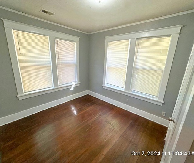 empty room featuring ornamental molding and dark wood-type flooring