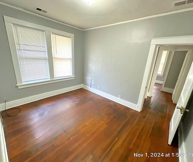 spare room with ornamental molding, wood finished floors, and baseboards