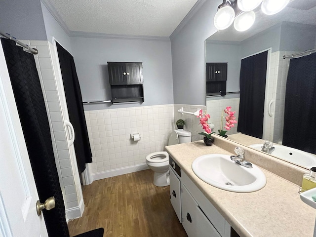 bathroom featuring tile walls, wood-type flooring, a textured ceiling, crown molding, and vanity